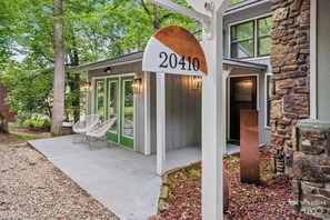 Une maison moderne avec une façade en pierre, un porche doté de chaises et une boîte aux lettres portant le numéro 20410.