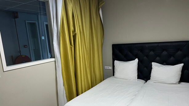Quarto de hotel com cama, janela e cortina.