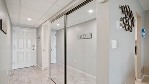 Un couloir avec une porte blanche, une cloison vitrée et un panneau fixé au mur.