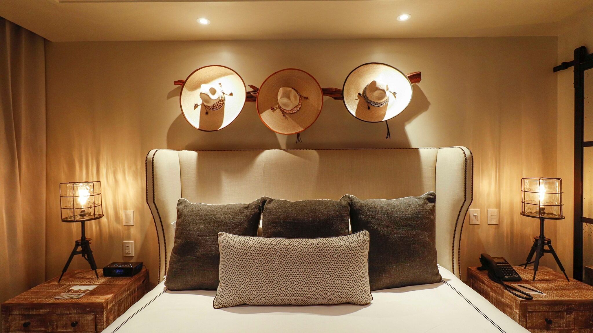 A hotel room with a large bed, three wall-mounted lamps, and two bedside tables with lamps.