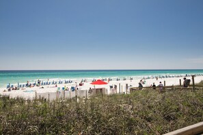 A beach with white sand, blue water, and a wooden fence in the foreground. - BEAUTIFUL STERLING SHORES GULF FRONT CONDO! (Destin)