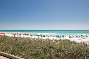 Una playa de arena blanca, agua turquesa cristalina y una fila de sillas y sombrillas azules.