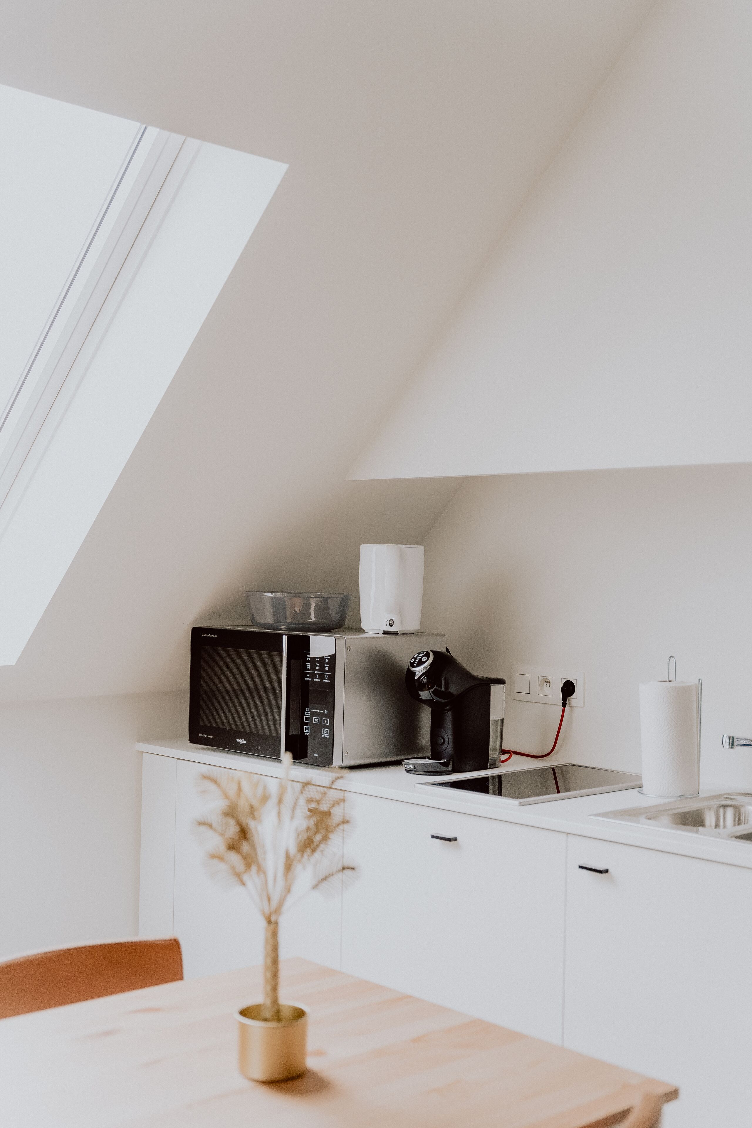 A modern kitchen with a microwave, coffee machine, and a bowl on the counter.