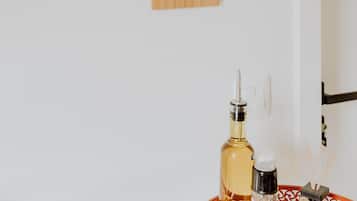 A wooden wall hanging with a message, a bottle of alcohol, and a small container with sticks on a table.