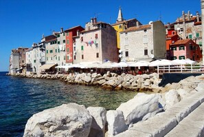 A coastal town with colorful buildings, a rocky shoreline, and outdoor seating areas. - Rovinj City Studio - A1 with balcony for couples (Rovinj)
