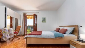 A bedroom with a bed, a desk, a chair, a table with a tablecloth, and a balcony door. - Rovinj City Studio - A1 with balcony for couples (Rovinj)