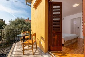A small, compact room with a bed, a wooden door with a window, and a small table with chairs. - Rovinj City Studio - A1 with balcony for couples (Rovinj)
