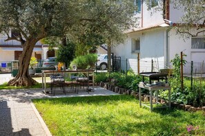 A garden with a table and chairs, a tree, and a building in the background. - Rovinj City Studio - A2 with balcony for couples (Rovinj)