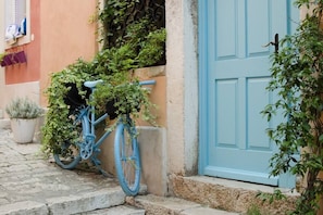 A blue bicycle parked on a cobblestone street next to a building with a blue door. - Rovinj City Studio - A2 with balcony for couples (Rovinj)