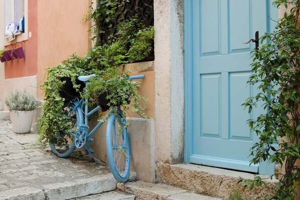A blue bicycle parked on a cobblestone street next to a building with a blue door. - Rovinj City Studio - A2 with balcony for couples (Rovinj)