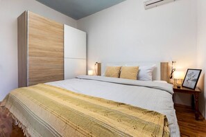 A bedroom with a bed, bedside tables, a wardrobe, and an air conditioning unit. - Rovinj City Studio - A2 with balcony for couples (Rovinj)