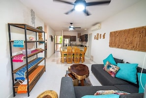 A modern living room with a sofa, a dining table, and a ceiling fan.
