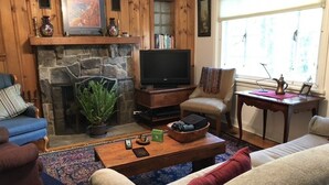 Een gezellige woonkamer met een stenen openhaard, een televisie en comfortabele zitplaatsen.