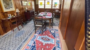 Een eethoek met een ronde tafel, stoelen en een kamerkleed met patroon.