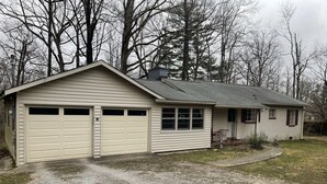 Een gelijkvloers huis met garage, klein terras en oprit met grind.