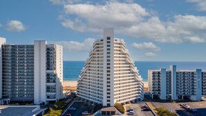 A modern hotel with a unique pyramid-shaped building, surrounded by other high-rise structures, offering ocean views. - Pyramid 11J by Seaside Vacations & Sales (Ocean City)