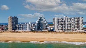 A beachfront hotel with multiple high-rise buildings, a sandy beach, and a clear blue sky. - Pyramid 11J by Seaside Vacations & Sales (Ocean City)