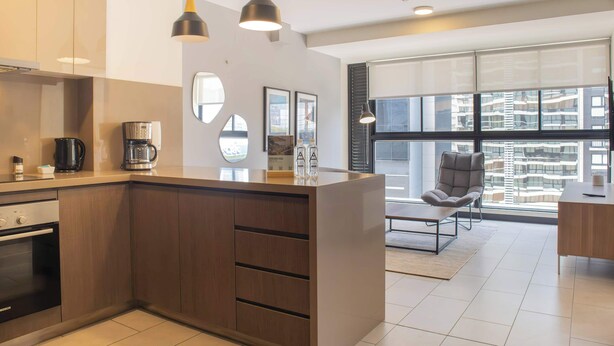 A modern kitchen with a central island, built-in oven, and pendant lighting.