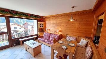 Een houten interieur met een eettafel voor vier personen, een bank en een lange bank.