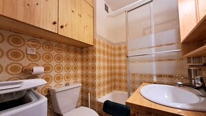 Une salle de bain avec des toilettes, un lavabo et une douche.