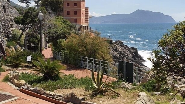 Un edificio costero con vista al mar y una montaña distante.