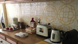 Una cocina con mostrador, tostadora, hervidor y cafetera.