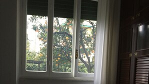 Una habitación con una cama, una ventana con persianas y una puerta.