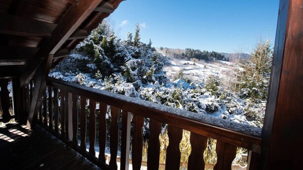 Ein Holzbalkon mit Blick auf eine verschneite Landschaft.