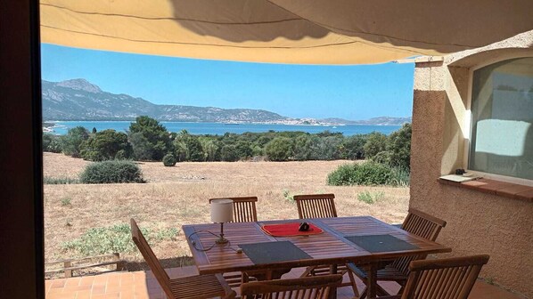 A patio with a table and chairs overlooking a scenic landscape with mountains and a body of water.