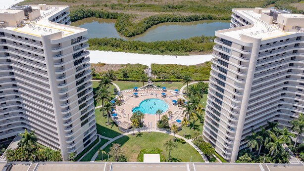 Un hôtel de grande hauteur doté d’une piscine centrale entourée de palmiers et offrant une vue sur la plage.