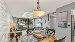 Un salon moderne avec une table à manger à plateau en verre, un canapé et un téléviseur.