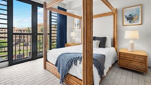 A four-poster bed with a blue throw blanket, a bedside table with a lamp, and a view of the outside balcony. - Rooftop Views, Private Beach Path & Resort Living in Palmas Del Mar (Humacao)