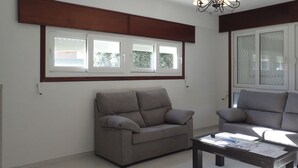 A living room with two grey sofas, a coffee table, and a chandelier. - Beachfront property (Malpica)