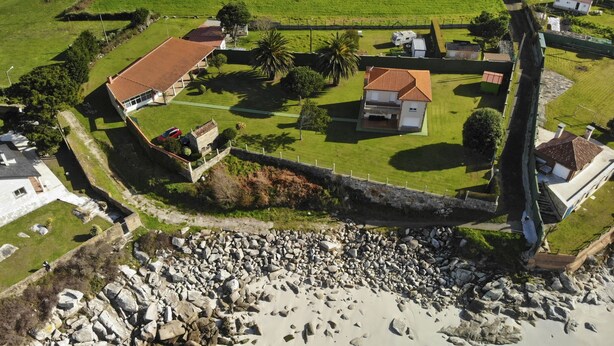 An aerial view of a coastal property with multiple buildings, a rocky shoreline, and a stone wall. - Beachfront property (Malpica)