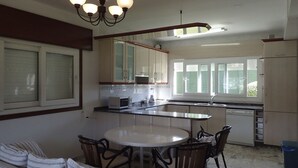 A kitchen with a dining table and chairs, a refrigerator, and a window. - Beachfront property (Malpica)