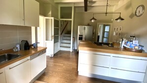 A kitchen with wooden flooring, white cabinets, a central island, and a refrigerator.