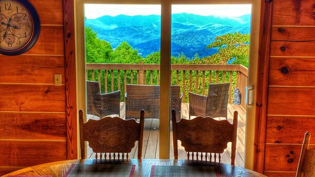 Una cabaña de madera con un balcón que da a un paisaje montañoso.