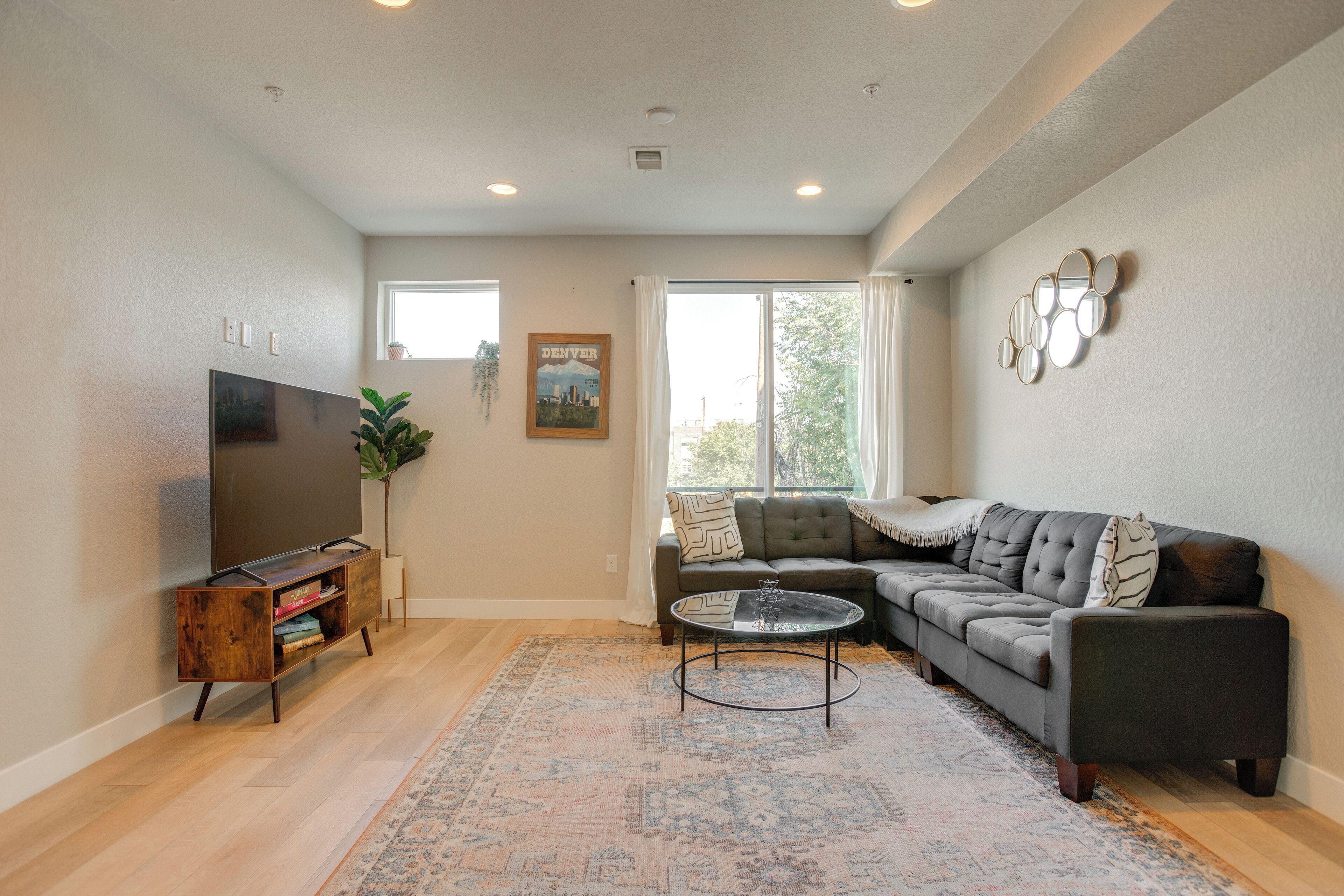 A living room with a sectional sofa, a flat-screen TV, a coffee table, and a patterned rug.