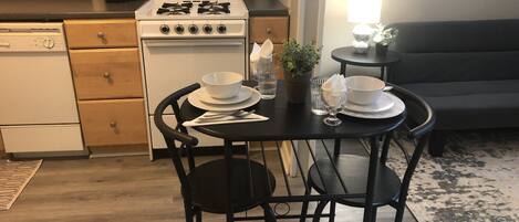 Uma cozinha compacta com fogão, máquina de lavar louça e mesa de jantar posta com pratos, tigelas e copos.