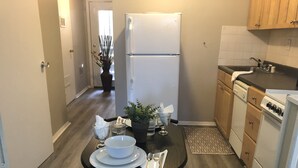 A compact kitchen with a dining table set for two, a refrigerator, a stove, and a sink.