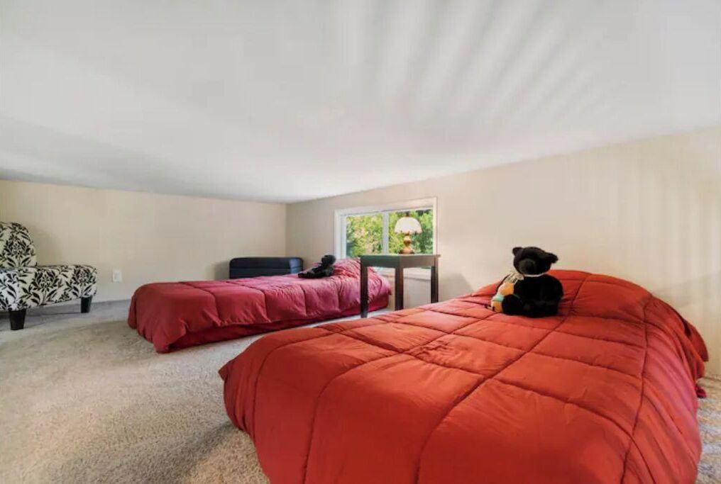 A bedroom with two beds, a chair, and a small table.