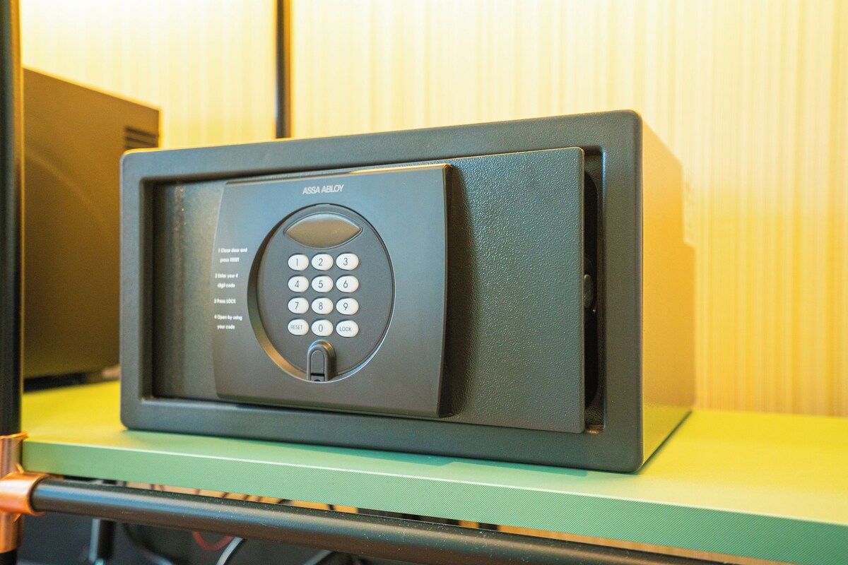 A black electronic device with a keypad, possibly a security system, on a green surface.