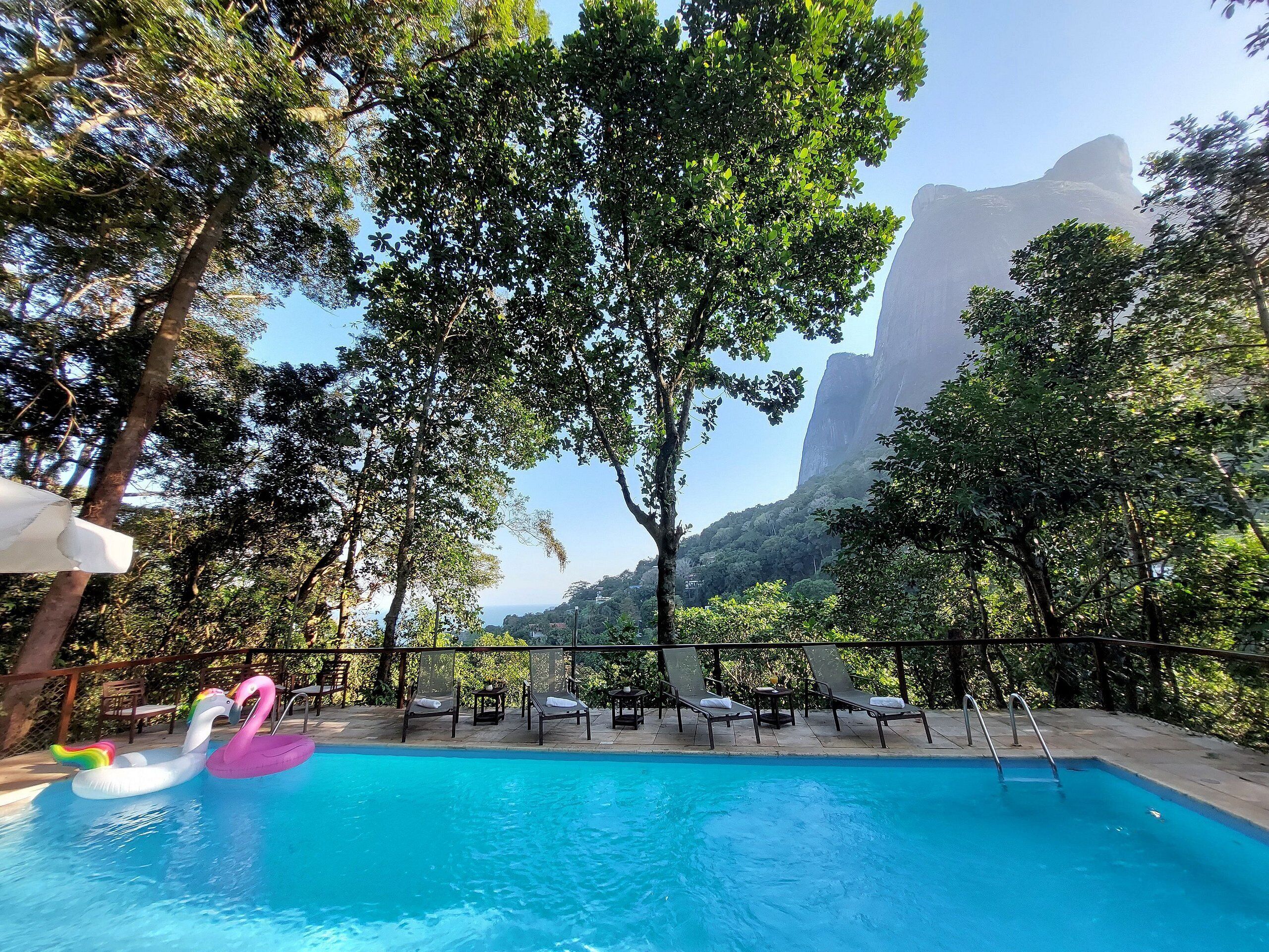 Una piscina al aire libre, sombrillas, sillones reclinables de piscina