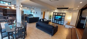 A modern living room with a black sofa, a glass coffee table, and a TV mounted on the wall.