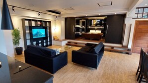A modern living room with a TV, sofas, a dining table, and a staircase leading to a bedroom. - Pedra Bonita Flats (Rio de Janeiro)