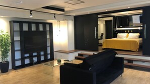 A modern living room with a black sofa, a glass coffee table, and a large flat-screen TV. - Pedra Bonita Flats (Rio de Janeiro)