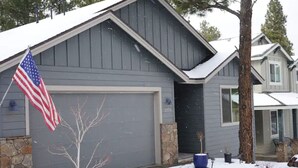 A residential house with a garage, a stone foundation, and an American flag. - Blue Mountain Cabin Escape/AC/Pet Friendly (Flagstaff)