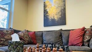 A chessboard on a wooden table in a living room with a sofa and patterned cushions. - Blue Mountain Cabin Escape/AC/Pet Friendly (Flagstaff)