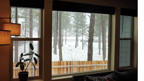 A room with a large window overlooking a snowy forest. - Blue Mountain Cabin Escape/AC/Pet Friendly (Flagstaff)