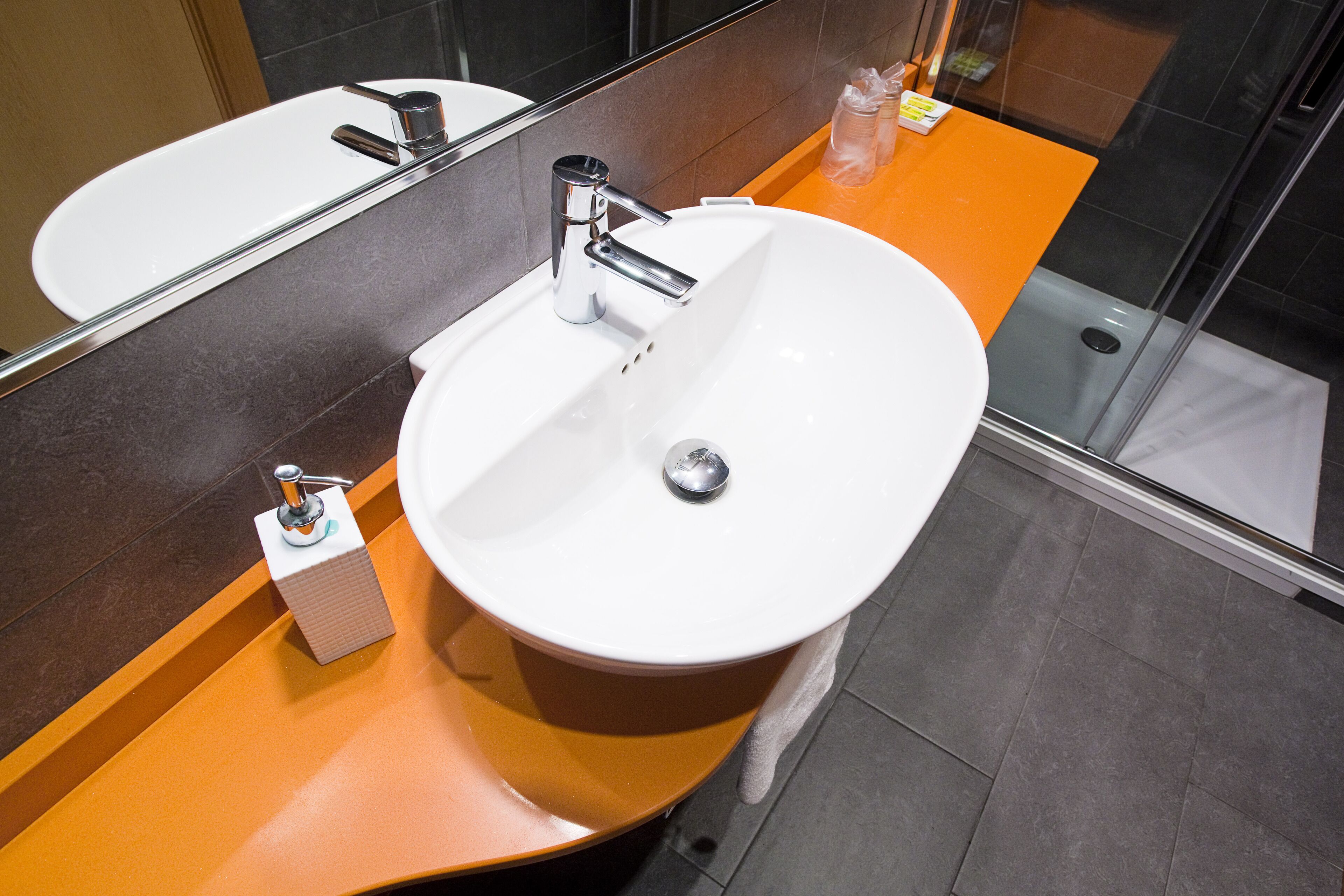 Un baño moderno con un lavamanos blanco, grifo cromado y cabina de ducha de vidrio.